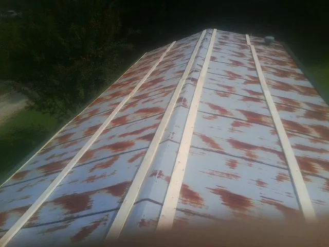 Rusted metal roof panels with new wood purlins before replacement — Storm Damage Roof Repair in Coldspring by Roofing Brothers