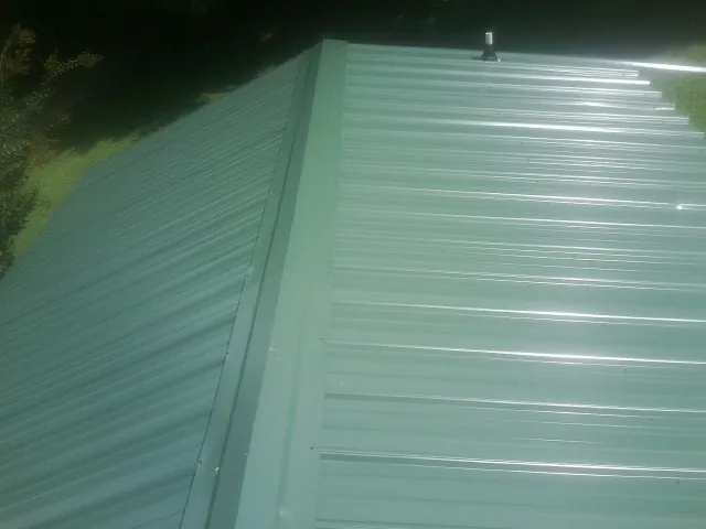 New green metal panels meeting at the ridge of a roof — Flat Roof Repair work by our crew in Coldspring