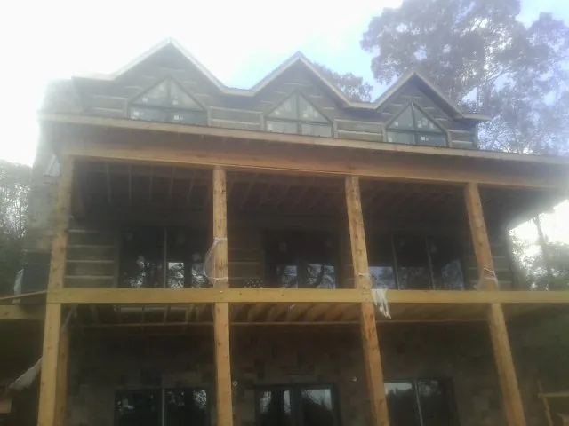 Dormers and porch framing on a large log home under construction — Roof Coating work by our crew in Coldspring