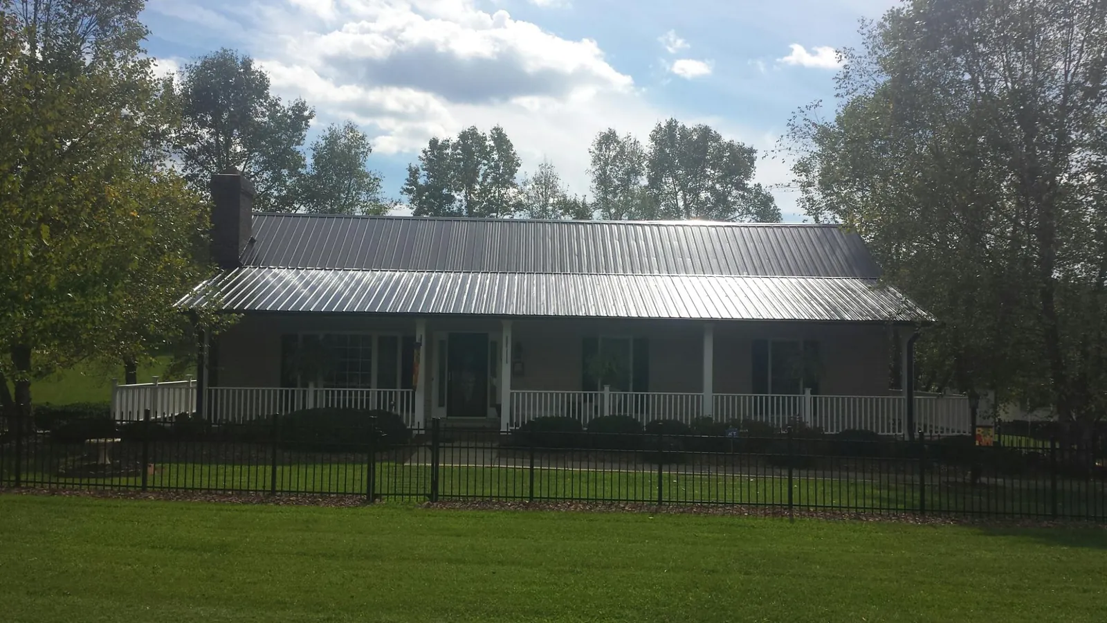 Gray metal roof on a brick ranch with a full width front porch — Gutter Guard Installation work by our crew in Coldspring