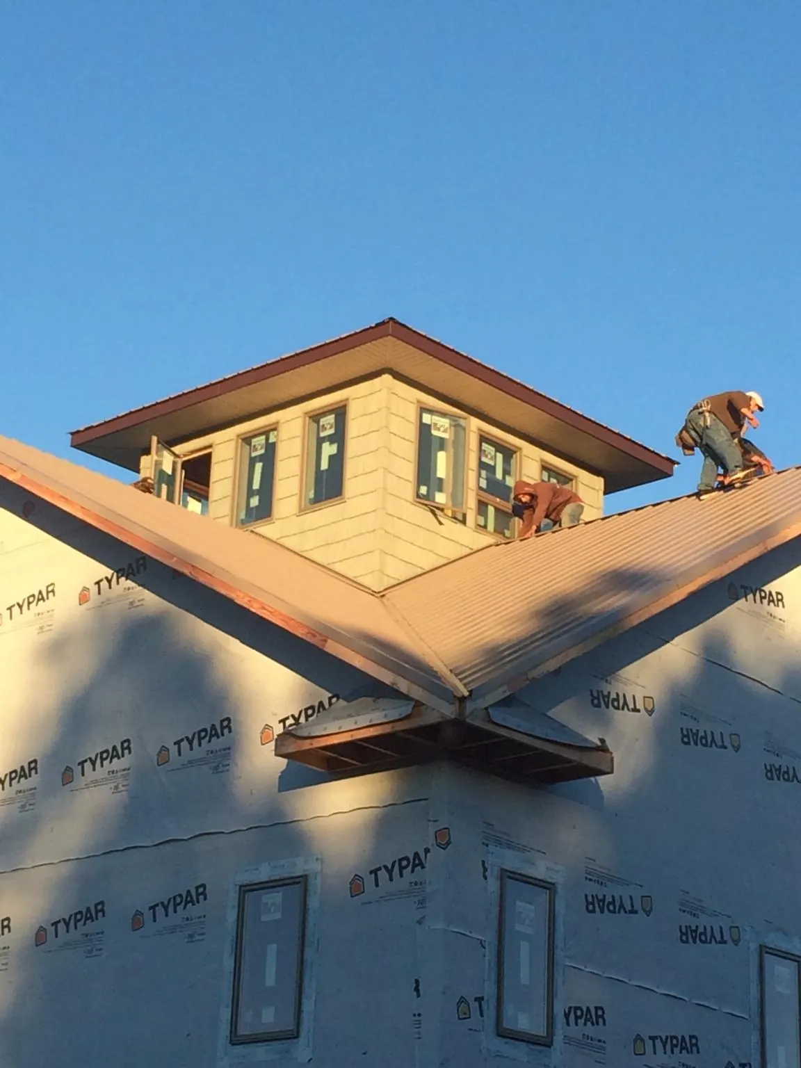 Roofers working around a rooftop cupola on a new metal roof at sunset — Roof Waterproofing in Coldspring by Roofing Brothers